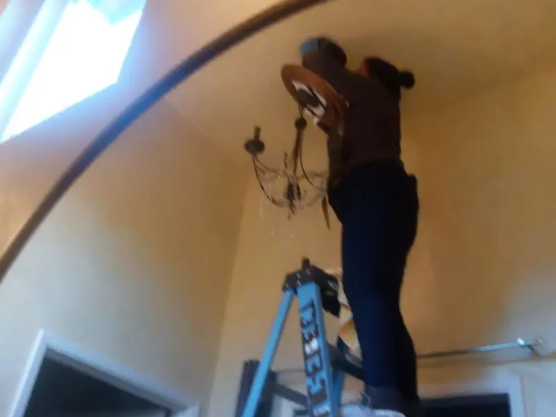 Electrician installing a chandelier in a Pearsall residence